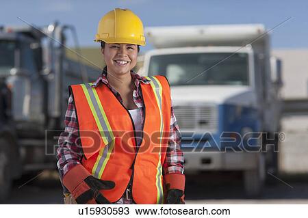 Stock Image - Portrait of female construction worker on building site. Fotosearch