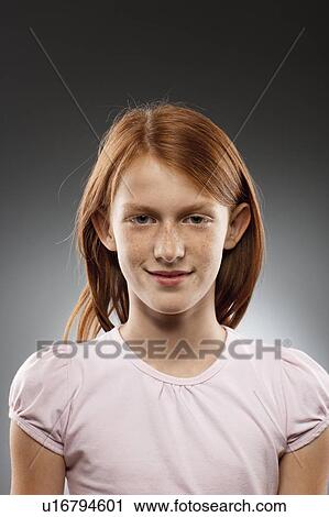 Stock Image - Portrait of redhead girl (10-11), studio shot. Fotosearch