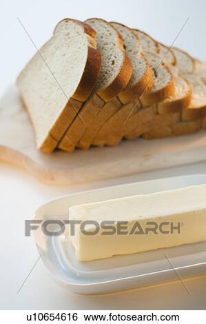 Stock Photograph - Sliced bread on chopping board beside butter. Fotosearch