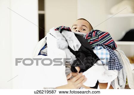 Stock Photo - South Africa, Man standing with pile of laundry. Fotosearch