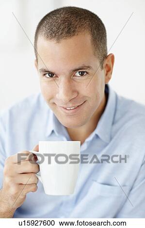 Stock Image - South Africa, Portrait of smiling man holding mug. Fotosearch