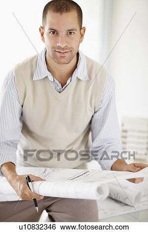Stock Photograph - South Africa, Portrait of young man holding blueprints. Fotosearch