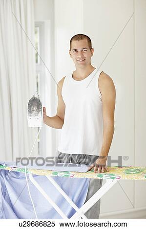 Stock Photography - South Africa, Portrait of young man ironing shirt. Fotosearch