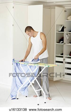Stock Photo - South Africa, Young man ironing shirt. Fotosearch