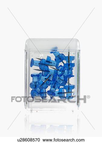 Stock Image - Studio shot of blue thumbtacks in glass cube. Fotosearch