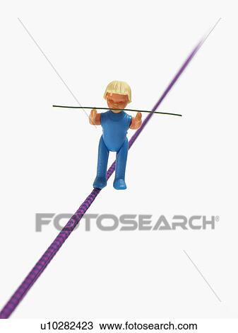 Studio shot of figurine balancing on tightrope View Large Photo Image Stock Image - Studio shot of figurine balancing on tightrope. Fotosearch
