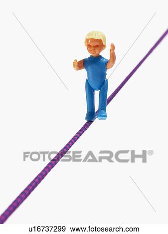 Stock Photo - Studio shot of figurine balancing on tightrope. Fotosearch