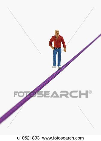 Studio shot of male figurine balancing on tightrope View Large Photo Image Stock Image - Studio shot of male figurine balancing on tightrope. Fotosearch