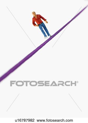 Stock Image - Studio shot of male figurine balancing on tightrope. Fotosearch