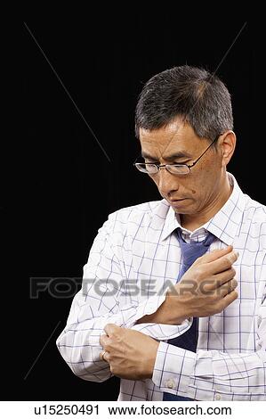 Studio shot of man buttoning cuff View Large Photo Image Stock Image - Studio shot of man buttoning cuff. Fotosearch