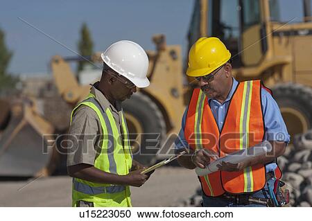 Stock Image - Two construction workers working on building site. Fotosearch