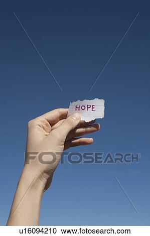 Stock Image - USA, Arizona, Winslow, Human hand holding paper with "hope" text on it. Fotosearch