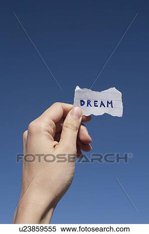 Stock Photography - USA, Arizona, Winslow, Human hand holding paper with "dream" text on it. Fotosearch