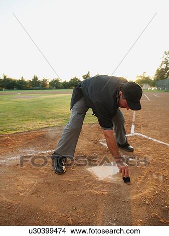 Picture - USA, California, Ladera Ranch, man drawing in sand on baseball diamond. Fotosearch