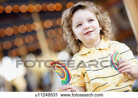Stock Image - USA, California, Los Angeles, Boy (4-5) holding lollipop and looking away. Fotosearch