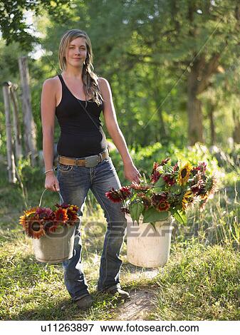 Stock Photo - USA, Colorado, Young woman carrying buckets with sunflowers. Fotosearch