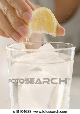 Stock Photo - USA, New Jersey, Jersey City, Close-up view of woman's hand squeezing lemon into refreshness drink. Fotosearch