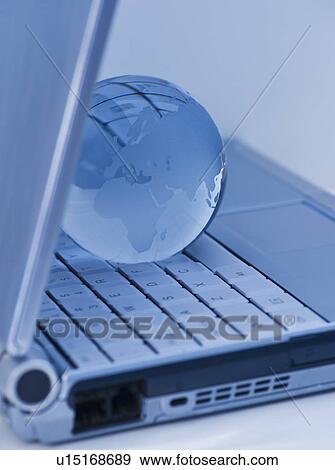 Stock Photo - USA, New Jersey, Jersey City, Close-up view of blue laptop and globe. Fotosearch