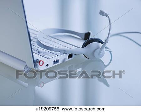 Stock Photograph - USA, New Jersey, Jersey City, Close-up view of open laptop and headset . Fotosearch