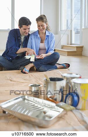 Stock Image - USA, New Jersey, Jersey City, Couple sitting near painting equipment in new home . Fotosearch