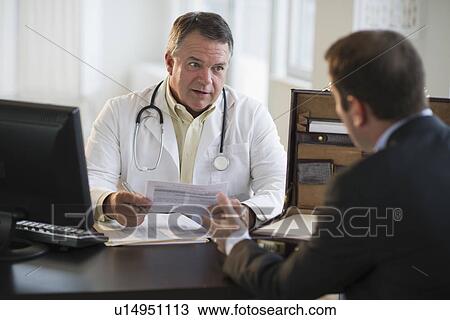 Stock Image - USA, New Jersey, Jersey City, Doctor discussing medical results with male patient in office. Fotosearch