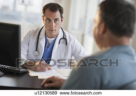 Stock Photo - USA, New Jersey, Jersey City, Doctor discussing medical results with male patient in office. Fotosearch
