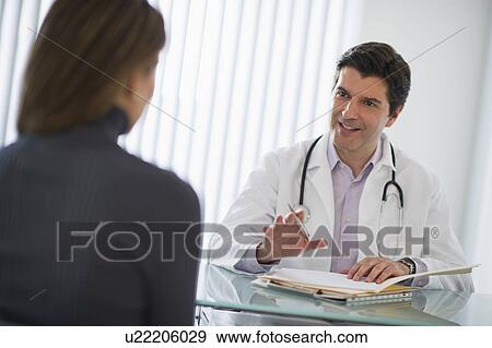 Stock Photo - USA, New Jersey, Jersey City, Doctor talking with female patient in office. Fotosearch