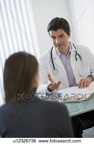 Stock Photograph - USA, New Jersey, Jersey City, Doctor talking with female patient in office. Fotosearch