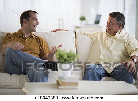 USA, New Jersey, Jersey City, Father and son talking on sofa in living room View Large Photo Image Stock Photo - USA, New Jersey, Jersey City, Father and son talking on sofa in living room. Fotosearch