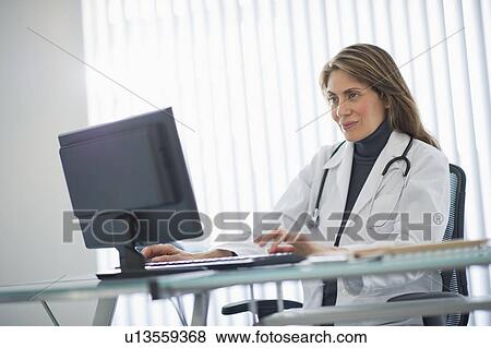 Stock Photo - USA, New Jersey, Jersey City, Female doctor using computer in office. Fotosearch