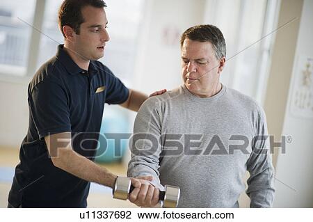 USA, New Jersey, Jersey City, Fitness instructor assisting man using hand weight in gym View Large Photo Image Stock Image - USA, New Jersey, Jersey City, Fitness instructor assisting man using hand weight in gym. Fotosearch