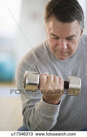 Stock Image - USA, New Jersey, Jersey City, Fitness instructor assisting man using hand weight in gym. Fotosearch