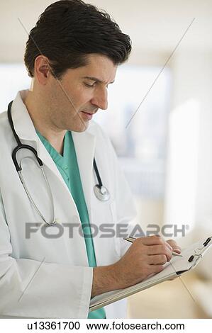 Stock Image - USA, New Jersey, Jersey City, Male doctor writing medical report. Fotosearch