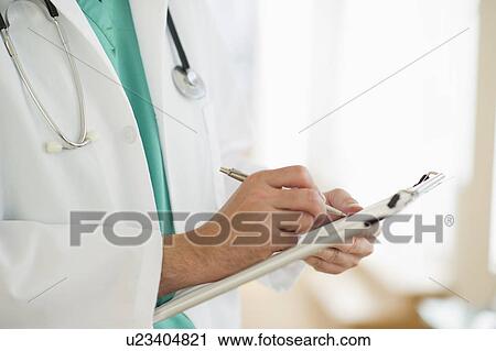 Stock Image - USA, New Jersey, Jersey City, Male doctor writing medical report. Fotosearch