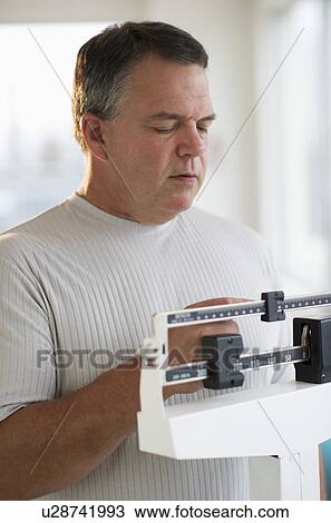 Stock Image - USA, New Jersey, Jersey City, Male patient on weighing scales in hospital. Fotosearch