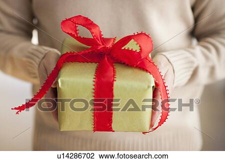Stock Image - USA, New Jersey, Jersey City, Man holding gift box in front of him. Fotosearch