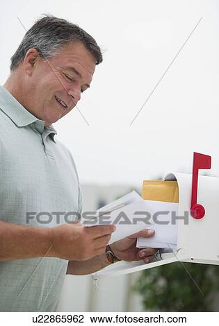 Stock Image - USA, New Jersey, Jersey City, Man checking mail in mailbox. Fotosearch