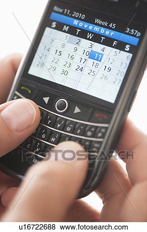 Stock Photo - USA, New Jersey, Jersey City, Man holding mobile phone with calendar. Fotosearch