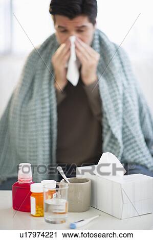 Stock Image - USA, New Jersey, Jersey City, Man with flu, blowing nose. Fotosearch