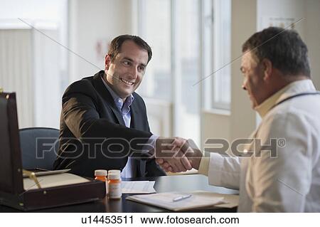 Stock Image - USA, New Jersey, Jersey City, Medical sales representative shaking hands with doctor in office. Fotosearch