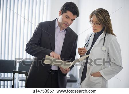 Stock Photo - USA, New Jersey, Jersey City, Medical sales representative talking with female doctor in office. Fotosearch