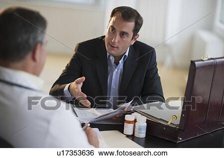 Stock Photograph - USA, New Jersey, Jersey City, Medical sales representative talking with doctor in office. Fotosearch