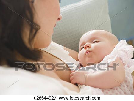 Stock Photo - USA, New Jersey, Jersey City, Mother holding baby daughter (2-5 months), reading letter. Fotosearch