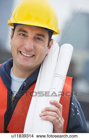 USA, New Jersey, Jersey City, Portrait of construction worker holding blueprints on construction site View Large Photo Image Picture - USA, New Jersey, Jersey City, Portrait of construction worker holding blueprints on construction site. Fotosearch