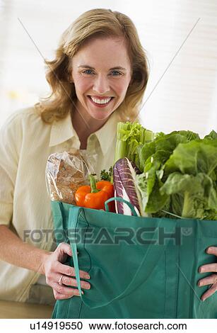 USA, New Jersey, Jersey City, Portrait of woman holding grocery bag in kitchen View Large Photo Image Stock Image - USA, New Jersey, Jersey City, Portrait of woman holding grocery bag in kitchen. Fotosearch