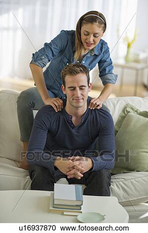 Stock Image - USA, New Jersey, Jersey City, Portrait of young couple relaxing on sofa. Fotosearch