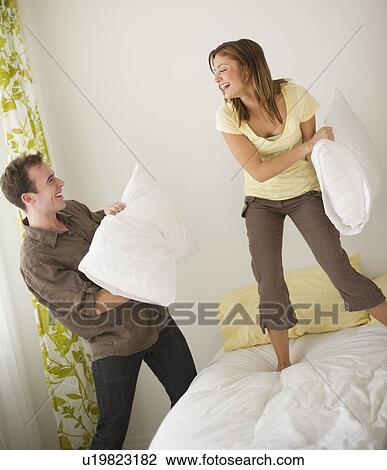 Stock Image - USA, New Jersey, Jersey City, Portrait of young couple fighting with pillow. Fotosearch