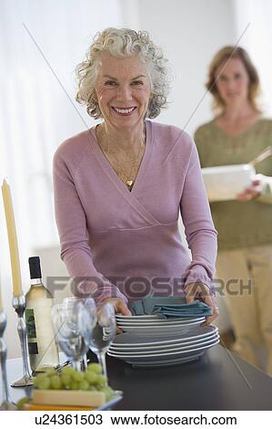 USA, New Jersey, Jersey City, Portrait of senior woman holding plates, with daughter in background View Large Photo Image Stock Image - USA, New Jersey, Jersey City, Portrait of senior woman holding plates, with daughter in background. Fotosearch