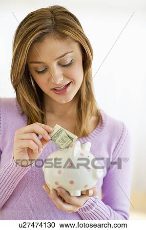 USA, New Jersey, Jersey City, Portrait of young woman putting banknote to piggybank View Large Photo Image Stock Image - USA, New Jersey, Jersey City, Portrait of young woman putting banknote to piggybank. Fotosearch