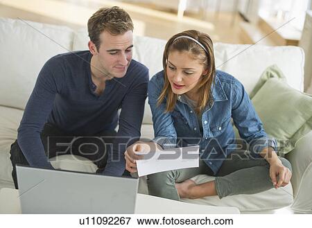 Stock Photo - USA, New Jersey, Jersey City, Portrait of young couple doing paperwork at home. Fotosearch